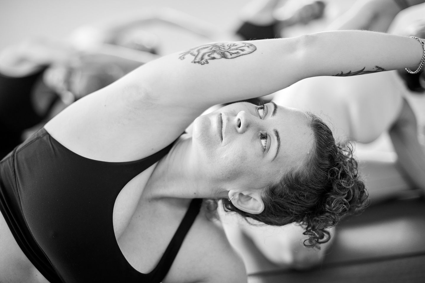 Sydney Yoga Photographer A yoga teacher with a tattoo on her arm performs a seated side bend yoga posture for a branding photoshoot in Sydney.