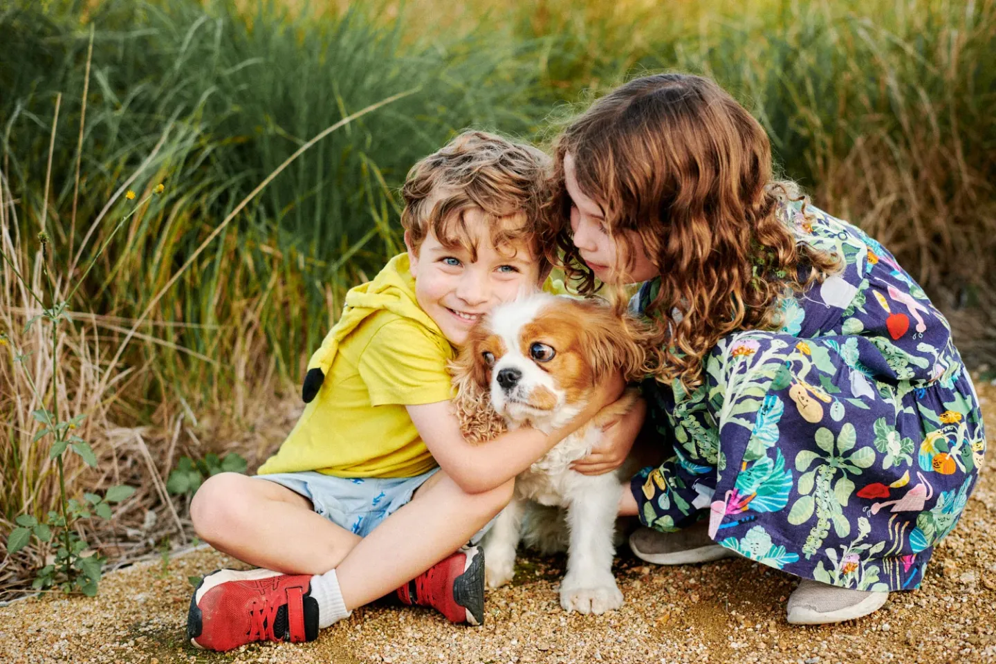 Family Photoshoot in Marrickville A boy and a girl sitting on the ground cuddling a puppy at a family photoshoot in Marrickville