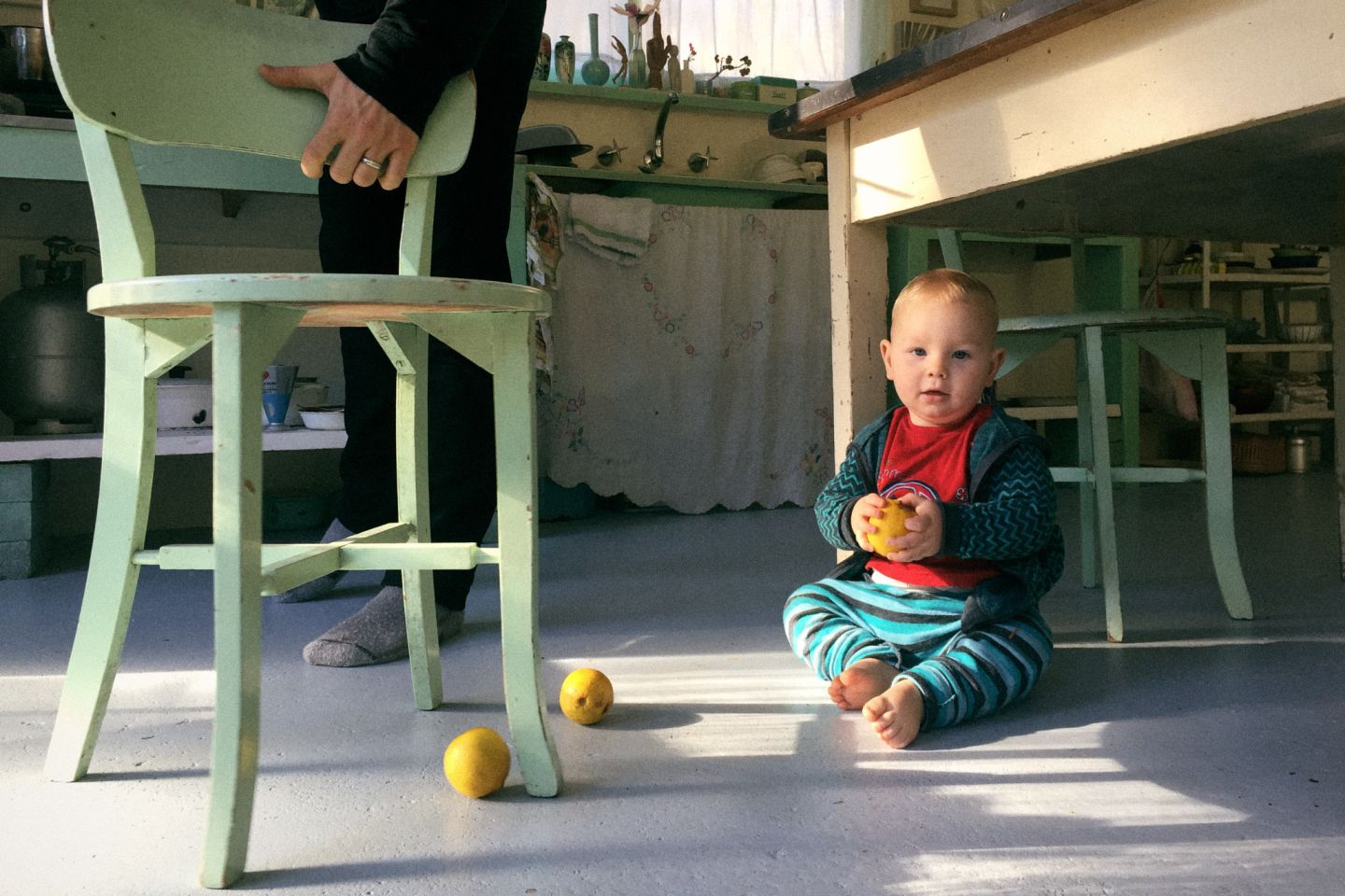 Sydney Baby Photography A documentary style family photo of a baby sitting on the floor holding a bright yellow lemon.
